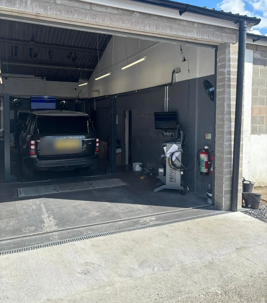A workshop bay at Mike’s Autos, with a car on the lift and test equipment by the door