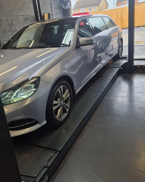 A silver Mercedes estate up on the lift in the workshop