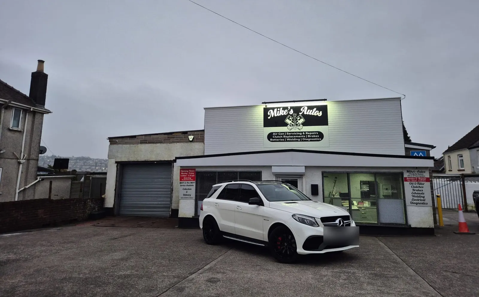 Mike’s Autos on Middle Road, Gendros, with the lit sign listing air con, servicing, clutches, brakes, batteries, welding and diagnostics