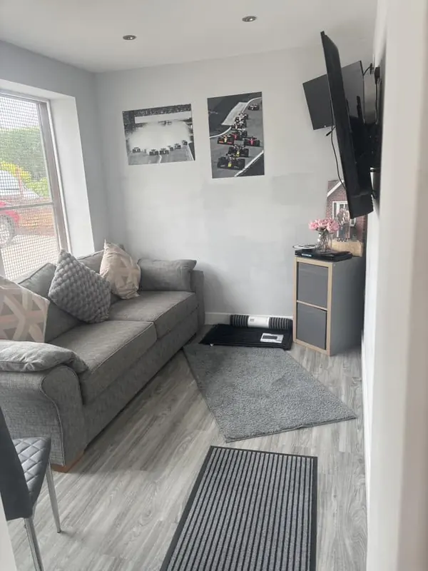 The customer waiting room, with a sofa, a TV and car prints on the wall